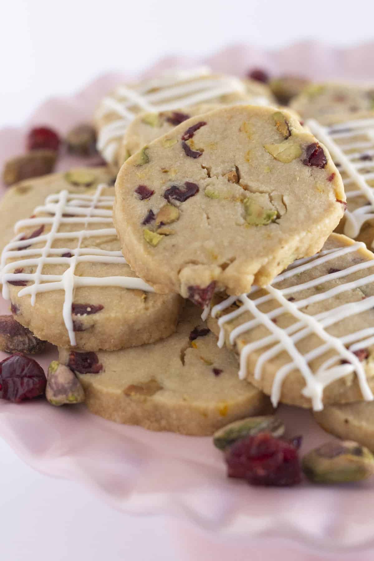 Une assiette de biscuits shortbread aux canneberges et pistaches, certains avec un filet de chocolat blanc.