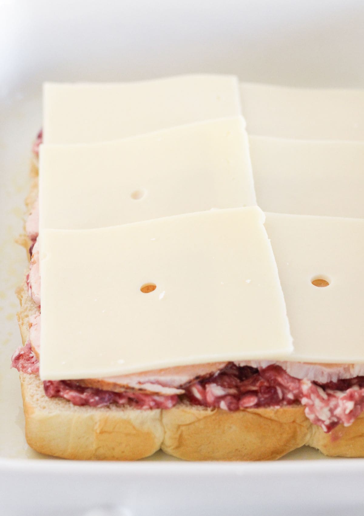 Topping the turkey with Swiss cheese.
