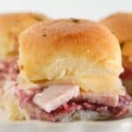 Three turkey cranberry sandwiches being served on a plate.