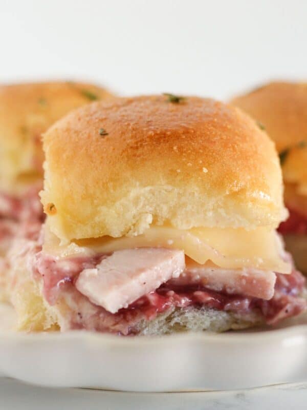 Three turkey cranberry sandwiches being served on a plate.