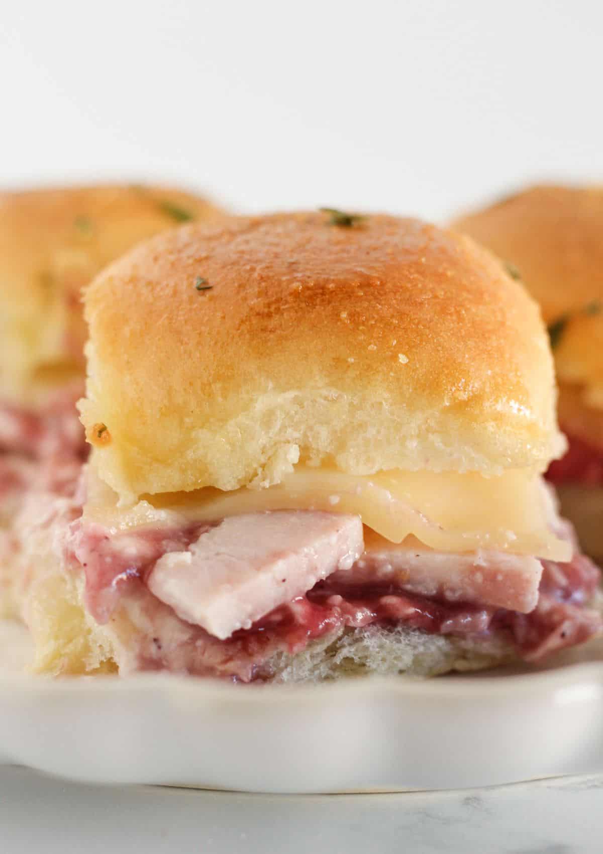 Three turkey cranberry sandwiches being served on a plate.