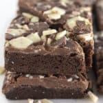 Peppermint bark brownies stacked and on a white plate.