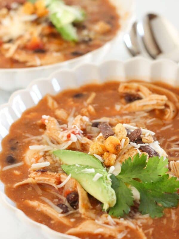 Two bowls of chicken enchilada soup with toppings.