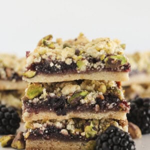 3 Blackberry Crumble bars stacked on each other with pistachios.