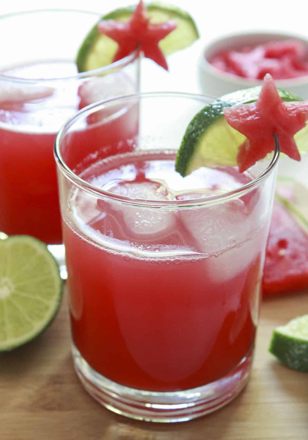 Watermelon limeade in glasses over ice with garnishes of both lime and watermelon stars.