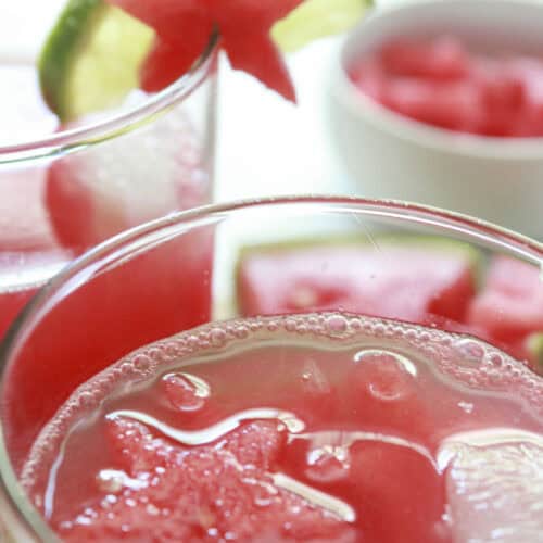 Watermelon limeade is served in glasses with a garnish of lime and watermelon.