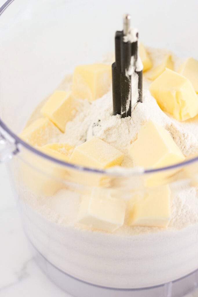 The dry ingredients and cold butter chunks in a food processor for sweet biscuits.