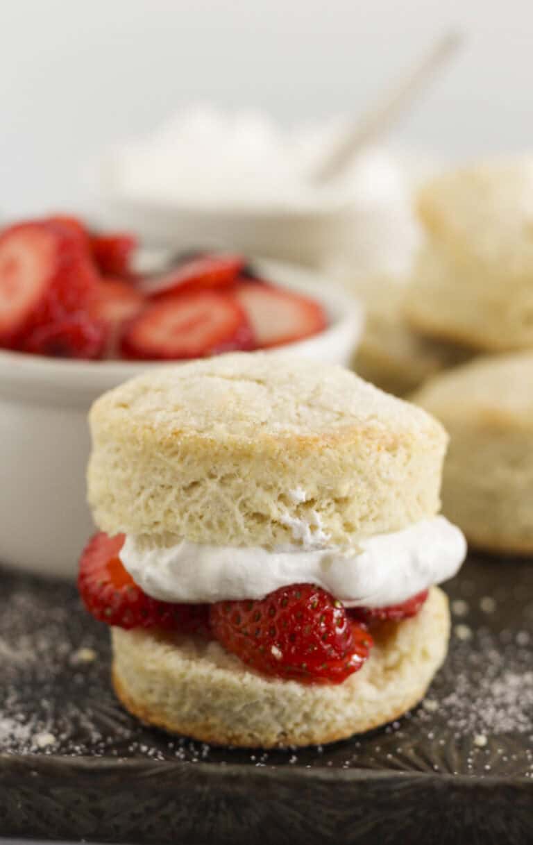 Sweet biscuits on a baking tray with whipped cream and strawberries.