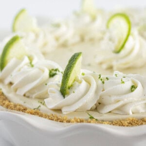 A key lime pie with homemade whipped cream and a graham cracker crust.