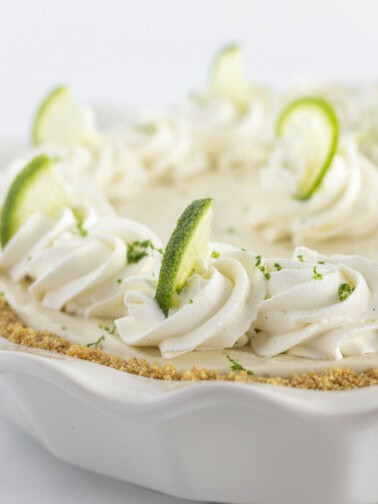 A key lime pie with homemade whipped cream and a graham cracker crust.