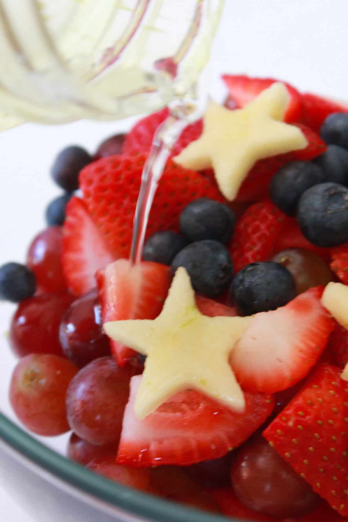 Pouring the lime simple syrup on the fresh fruit.