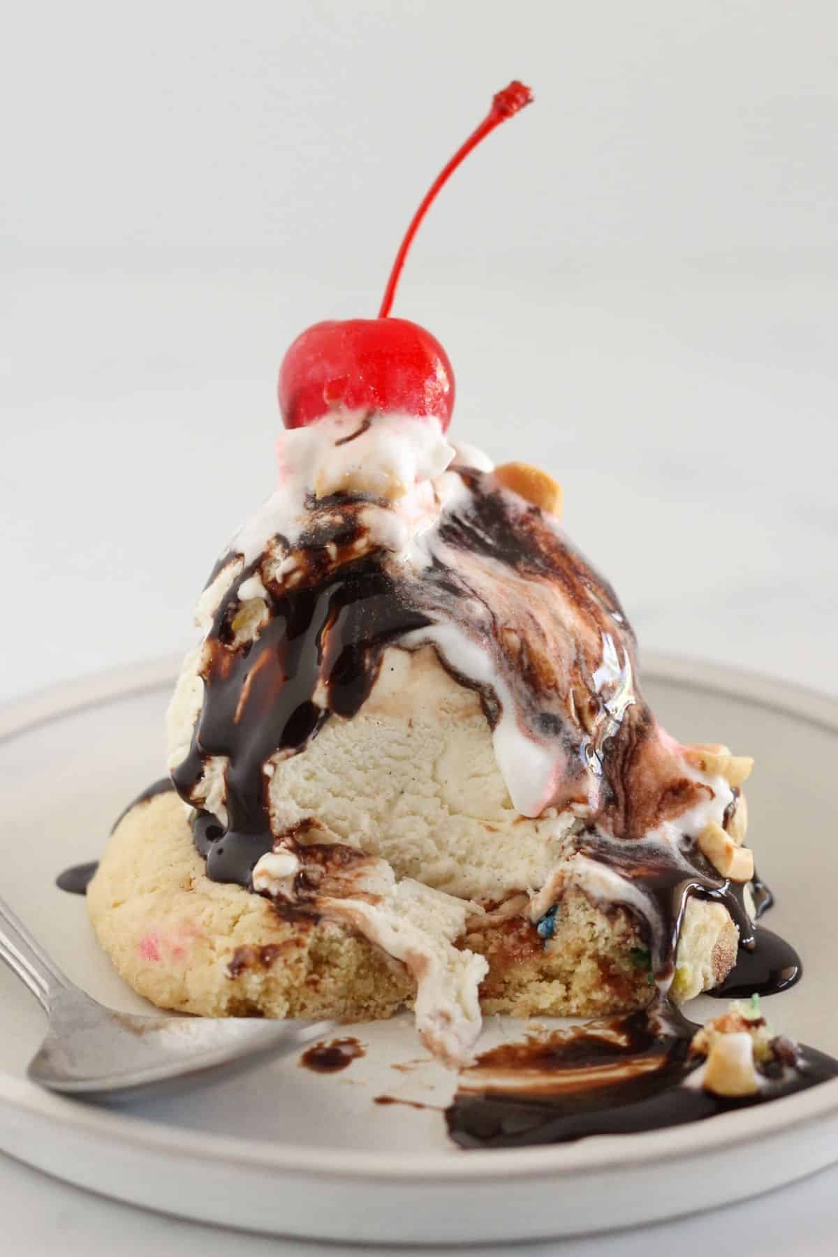 Ice cream sundae cookie on a plate with a bite taken.