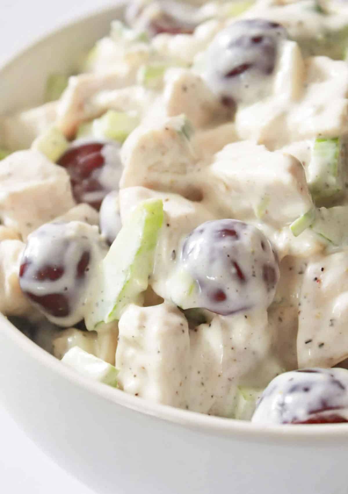 Chicken salad with grapes and almonds in a white bowl.