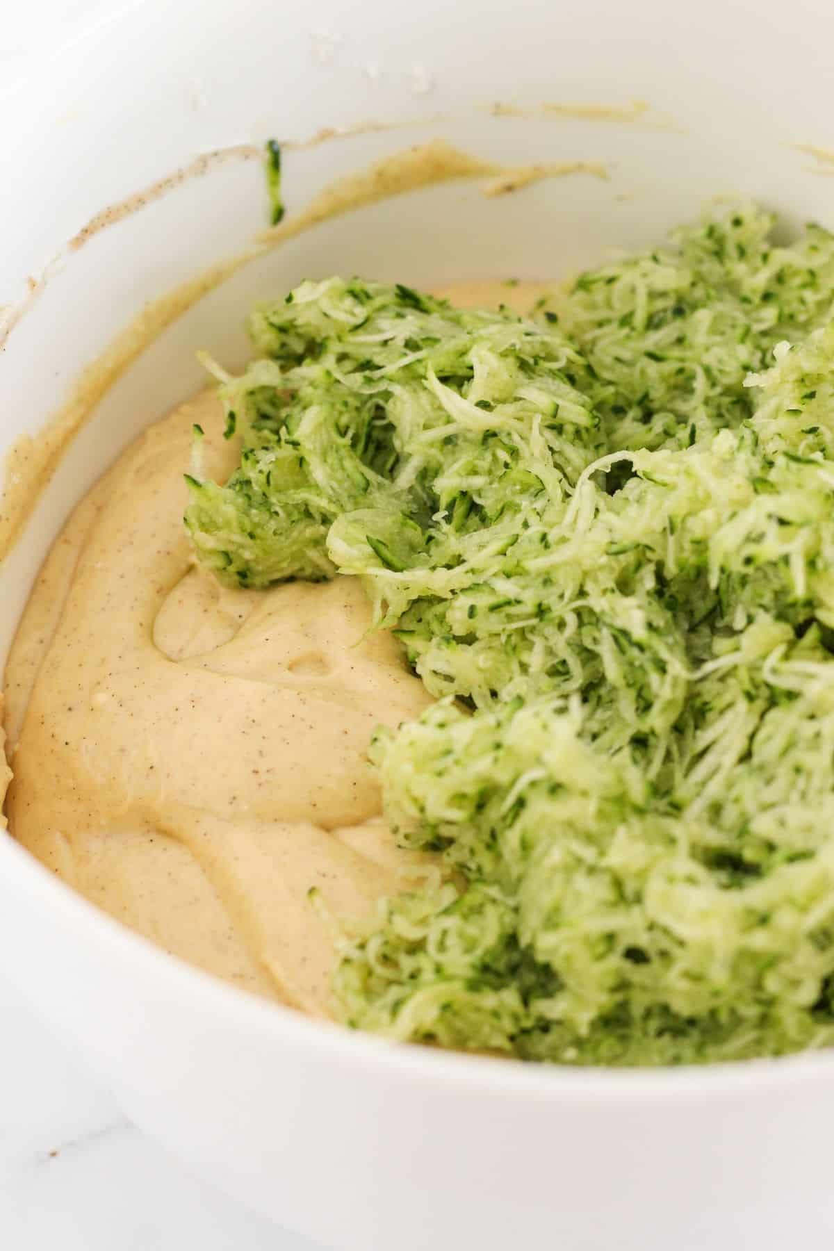 Adding the shredded zucchini to cake batter.