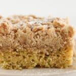 Golden brown zucchini cake with crumb topping on a plate.