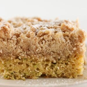 Golden brown zucchini cake with crumb topping on a plate.