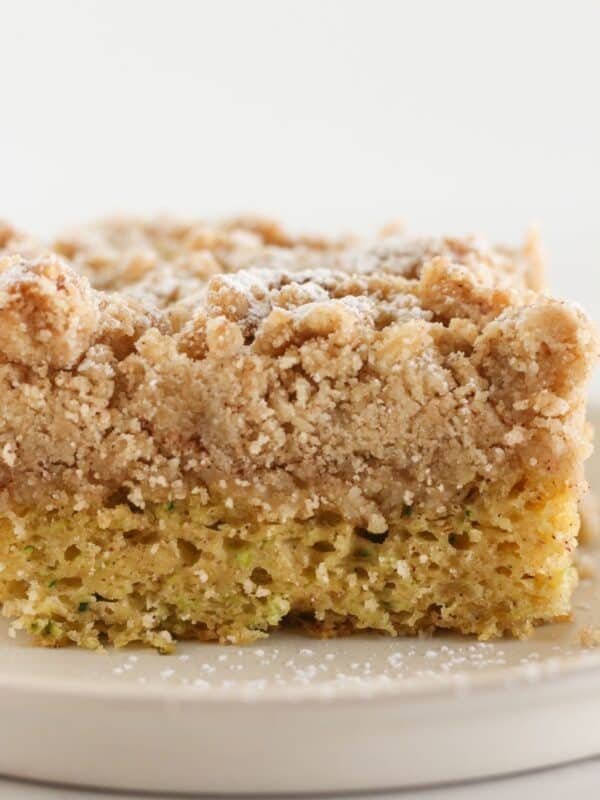 Golden brown zucchini cake with crumb topping on a plate.