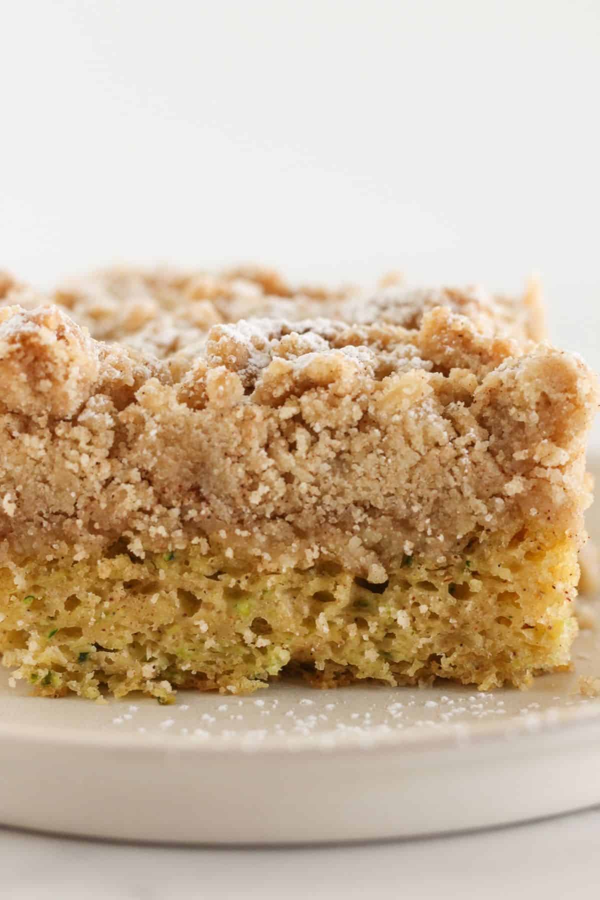 Golden brown zucchini cake with crumb topping on a plate.