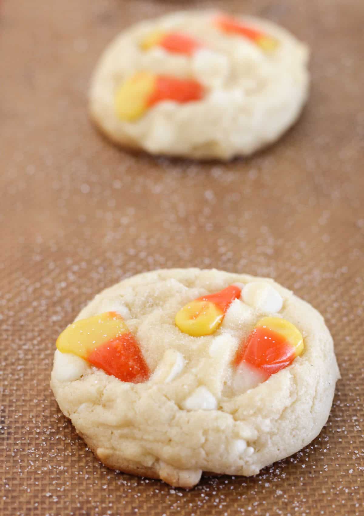 Topping the baked cookies with candy corn and sugar.