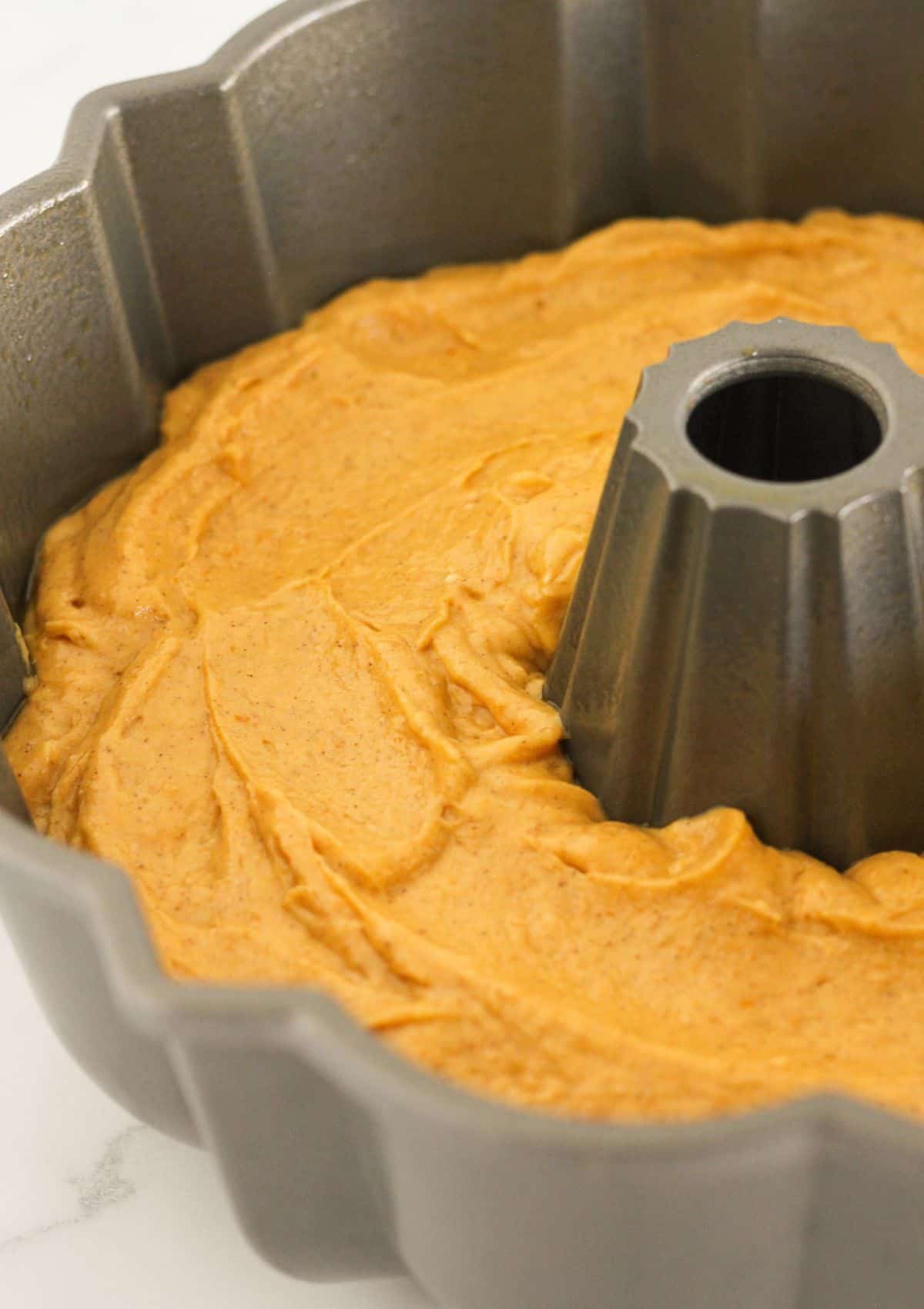 Adding the cake batter to a prepared bundt pan.
