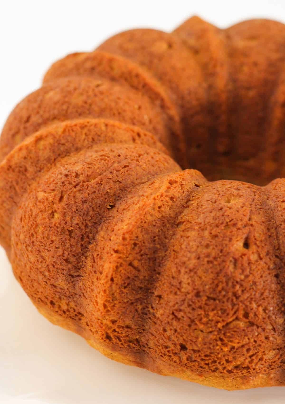 A baked pumpkin spice bundt cake on a cake plate.