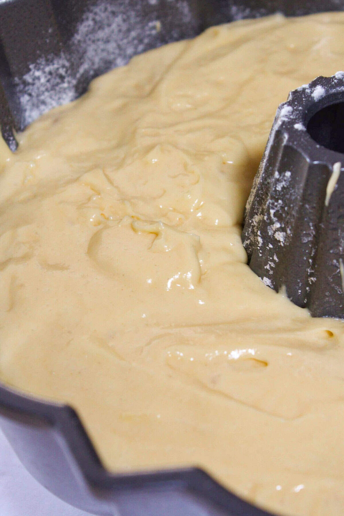 Making the cake batter and pouring part of it into a prepared bundt pan.
