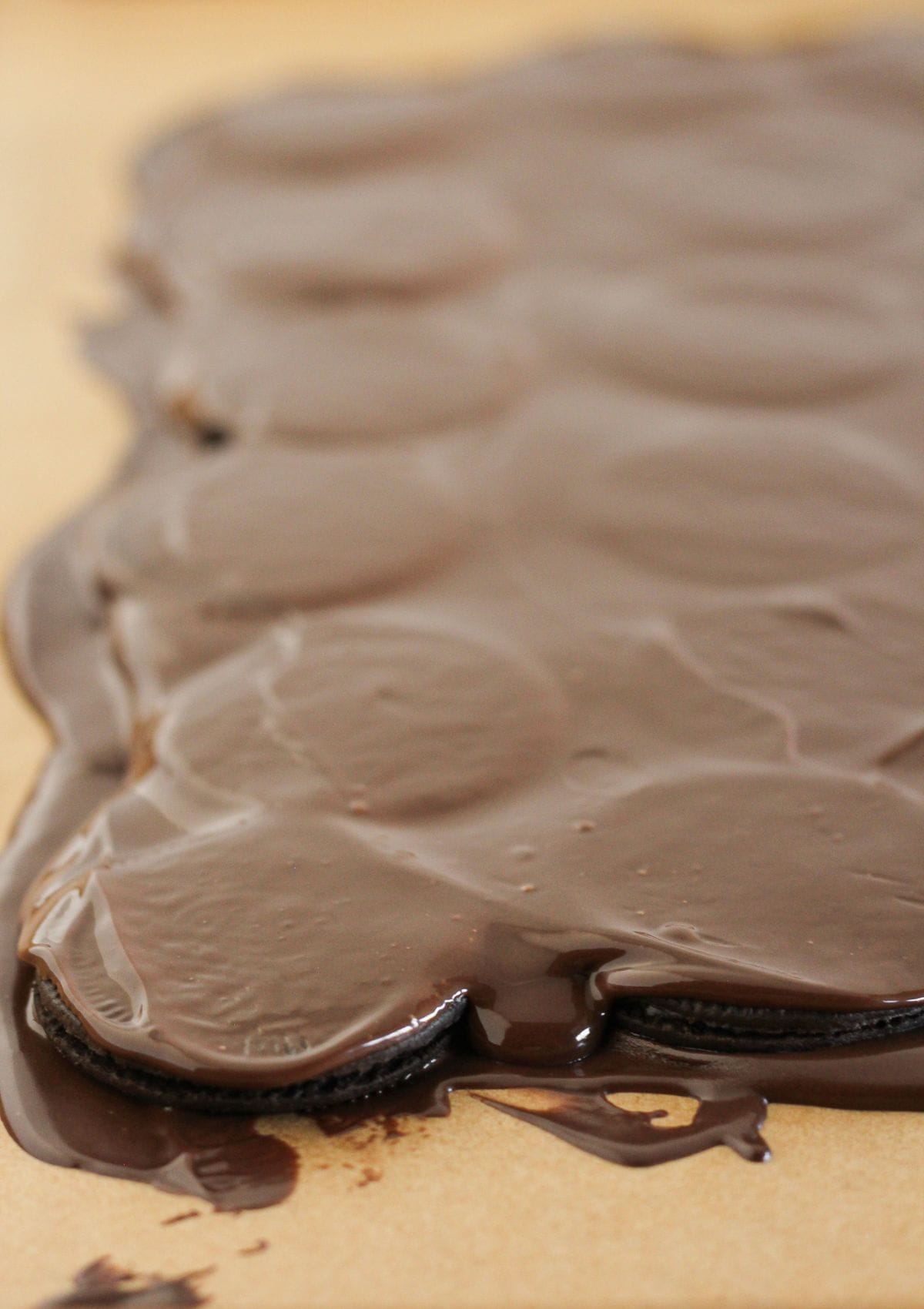 Topping the Oreos with more melted chocolate.