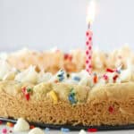 A birthday cookie cake with sprinkles and a candle.