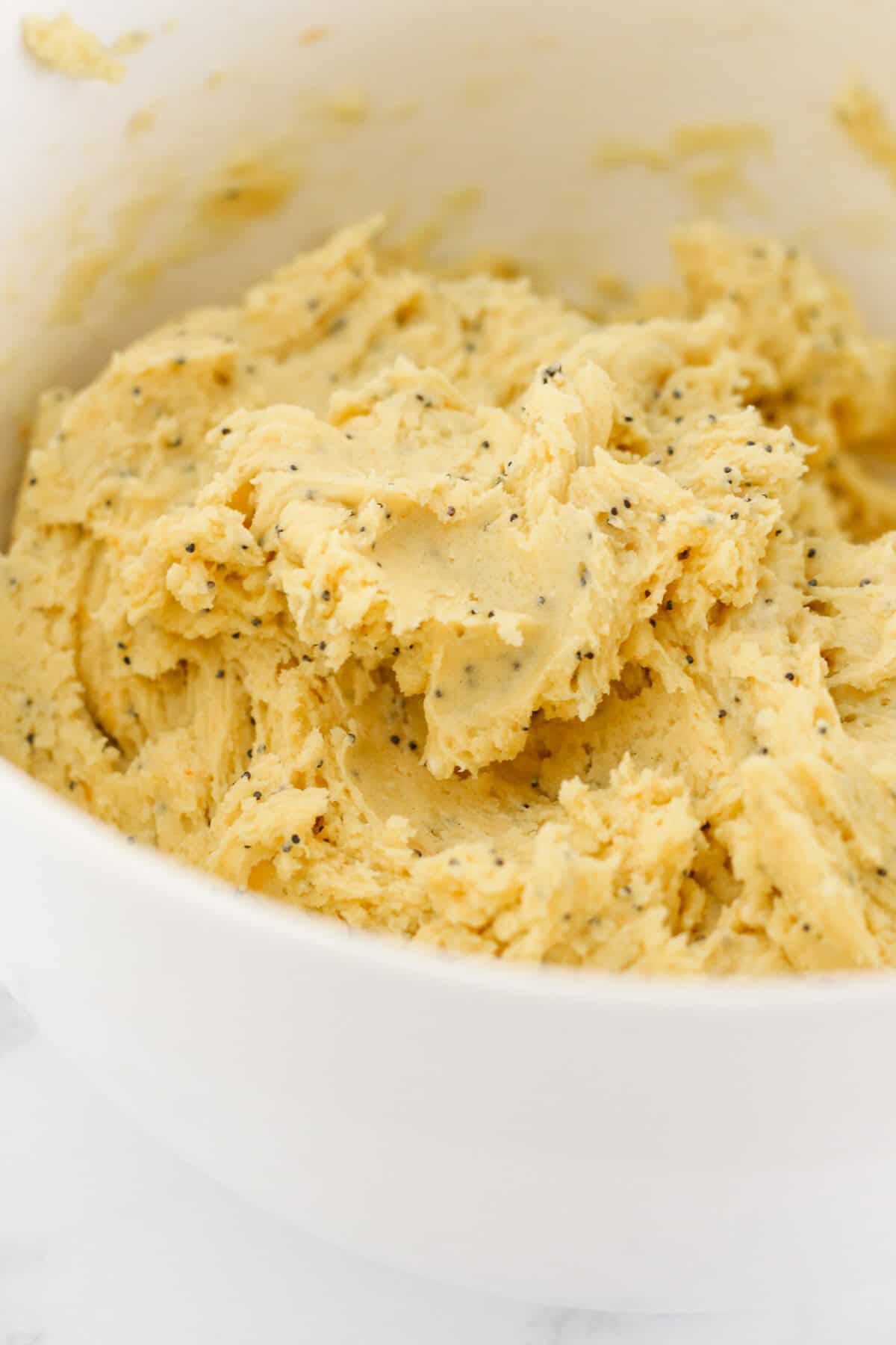 The finished lemon poppy seed cookie dough in a white bowl.