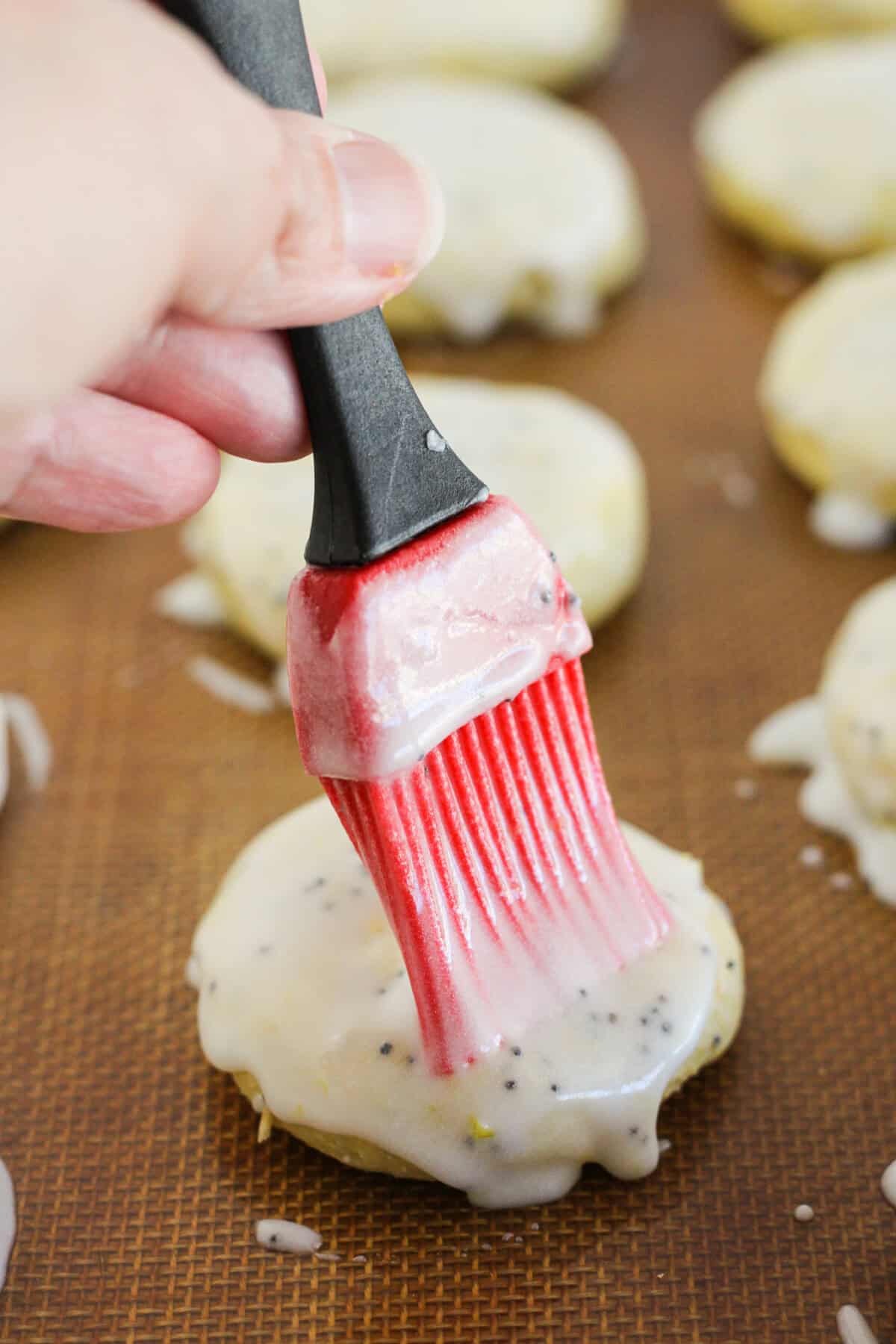 Brushing the lemon glaze on the baked cookies.