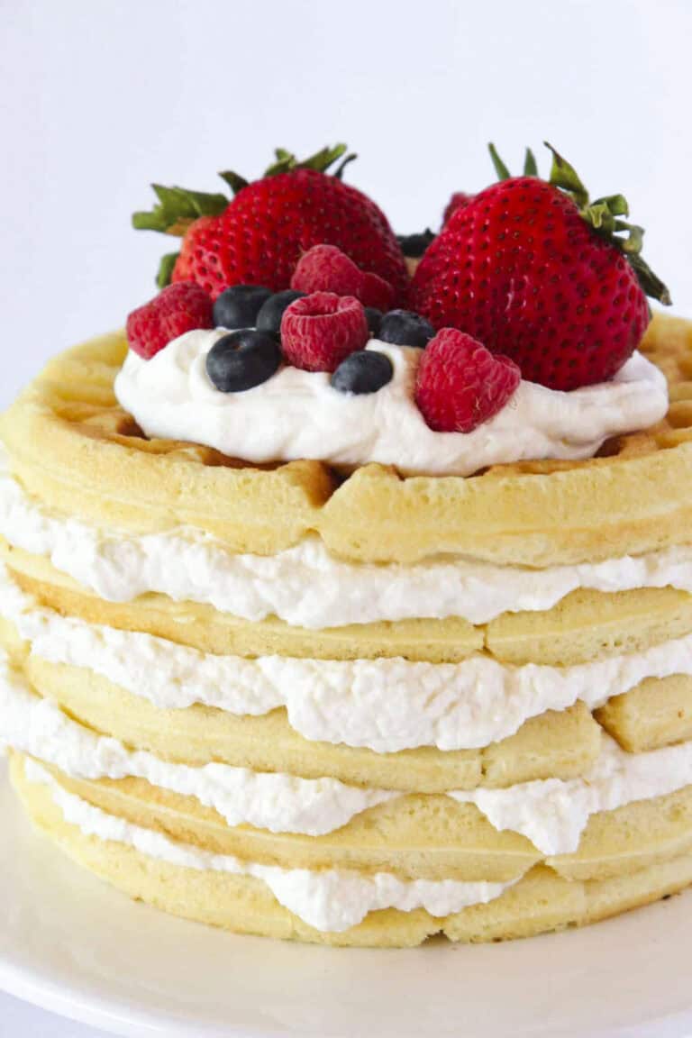 A waffle cake with homemade whipped cream and fresh berries.