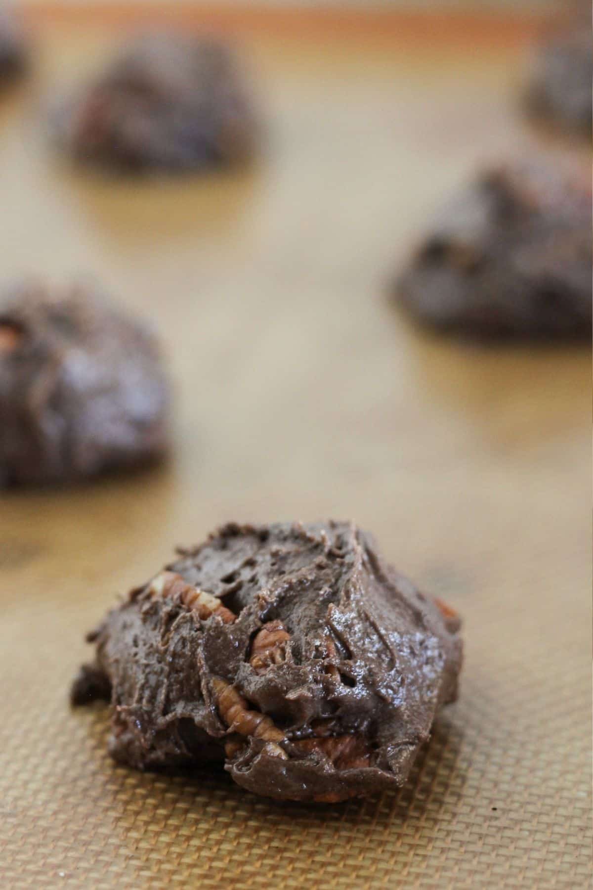 Scooped cookie dough on a lined baking sheet.