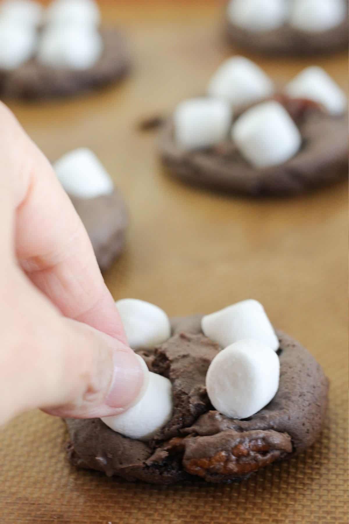 Adding marshmallows to the top of the partially baked cookie.