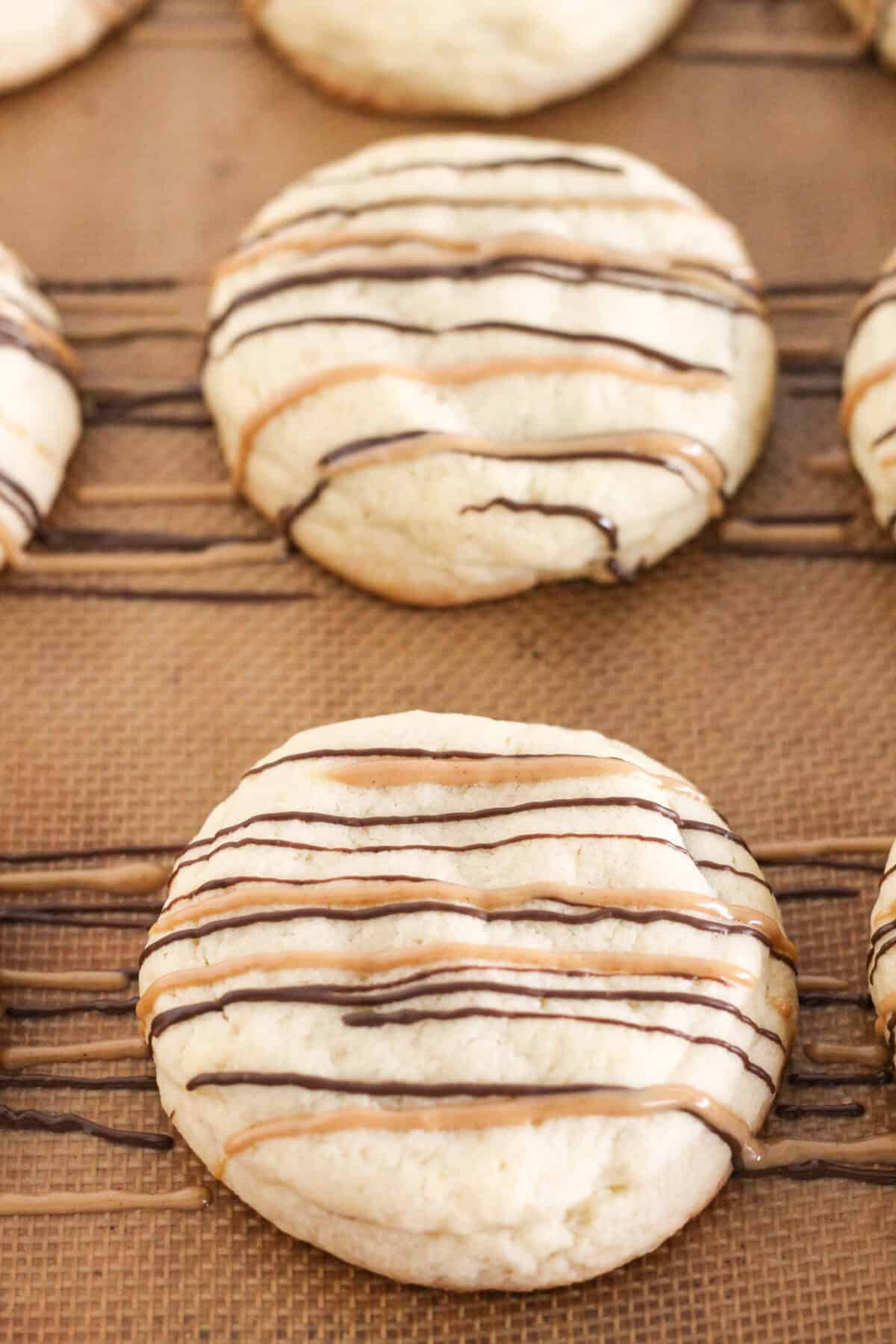Cookies on a baking sheet that are drizzled with chocolate.