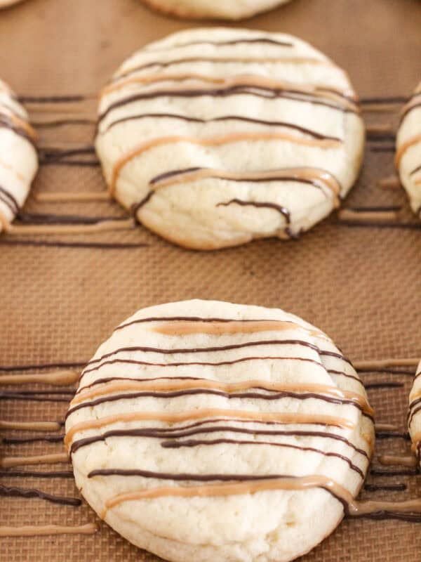 Cookies on a baking sheet that are drizzled with chocolate.