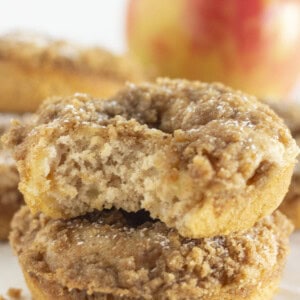 Apple crumb donuts stacked on each other with fresh apple inside.