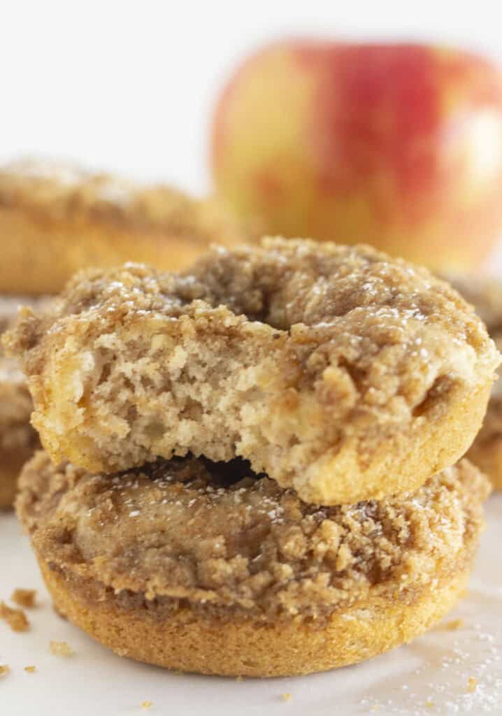 Apple crumb donuts stacked on each other with fresh apple inside.