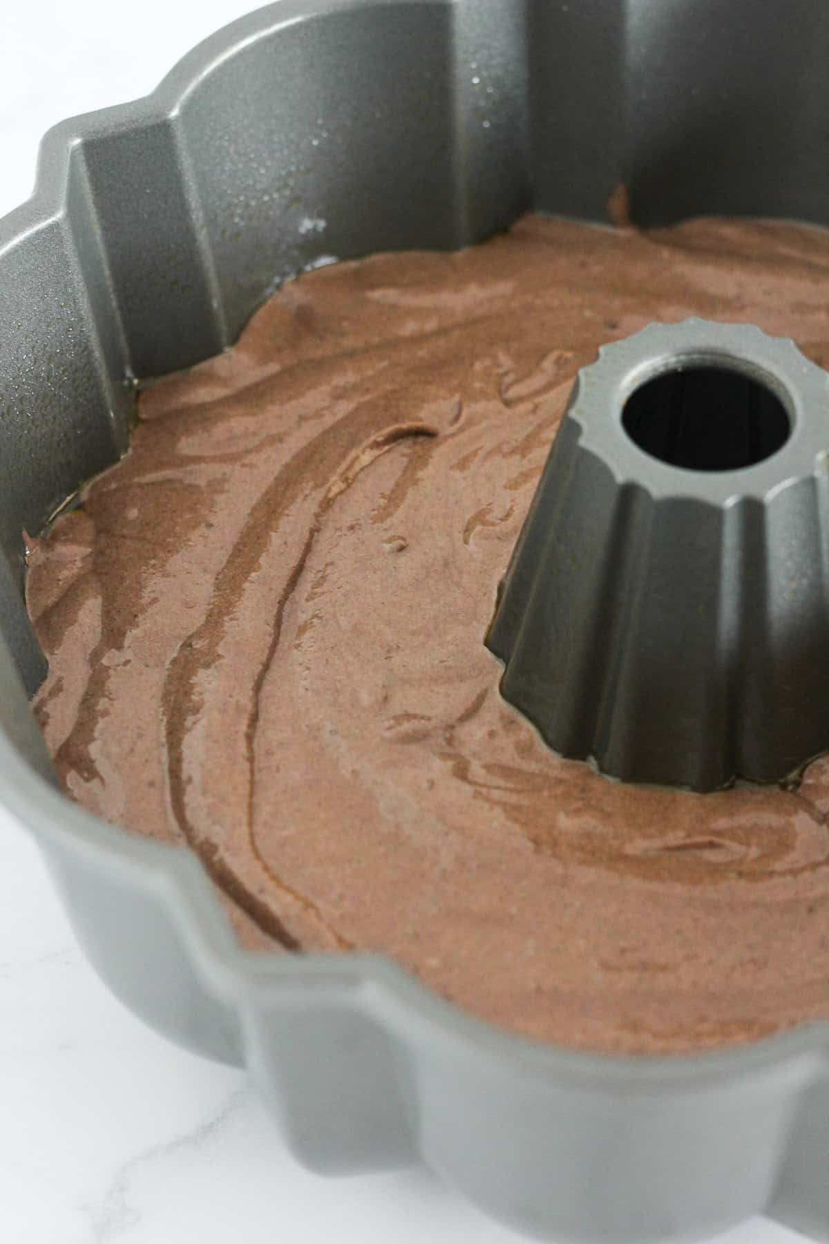 Adding the chocolate cake batter to the bundt pan.
