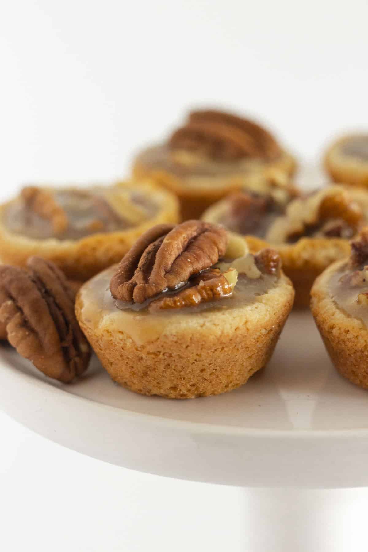 Pecan pie cookies on a white cake plate.