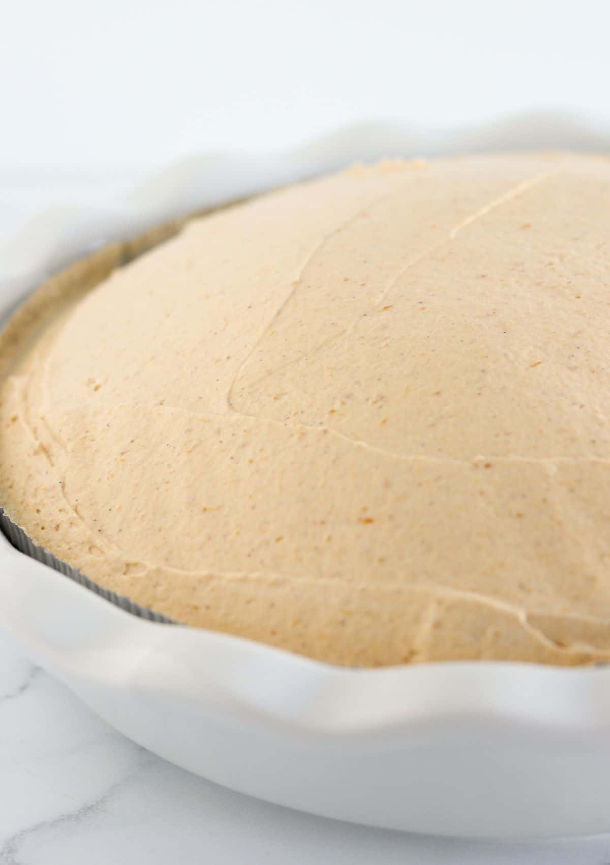 Adding the pumpkin mousse pie filling into the pie crust.