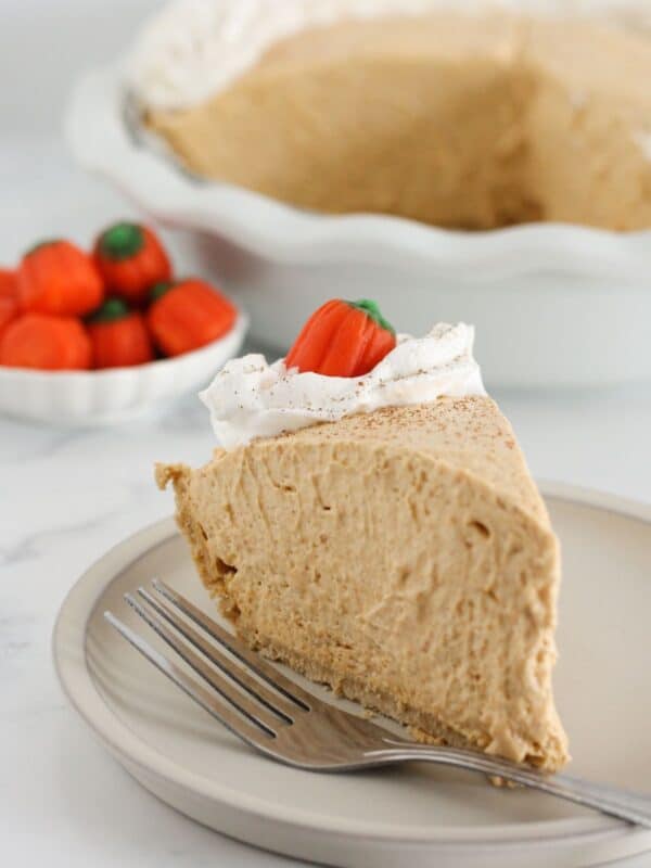 A slice of pumpkin mousse pie on a plate with whipped topping.