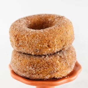 Two pumpkin spice donuts on an orange cake plate.