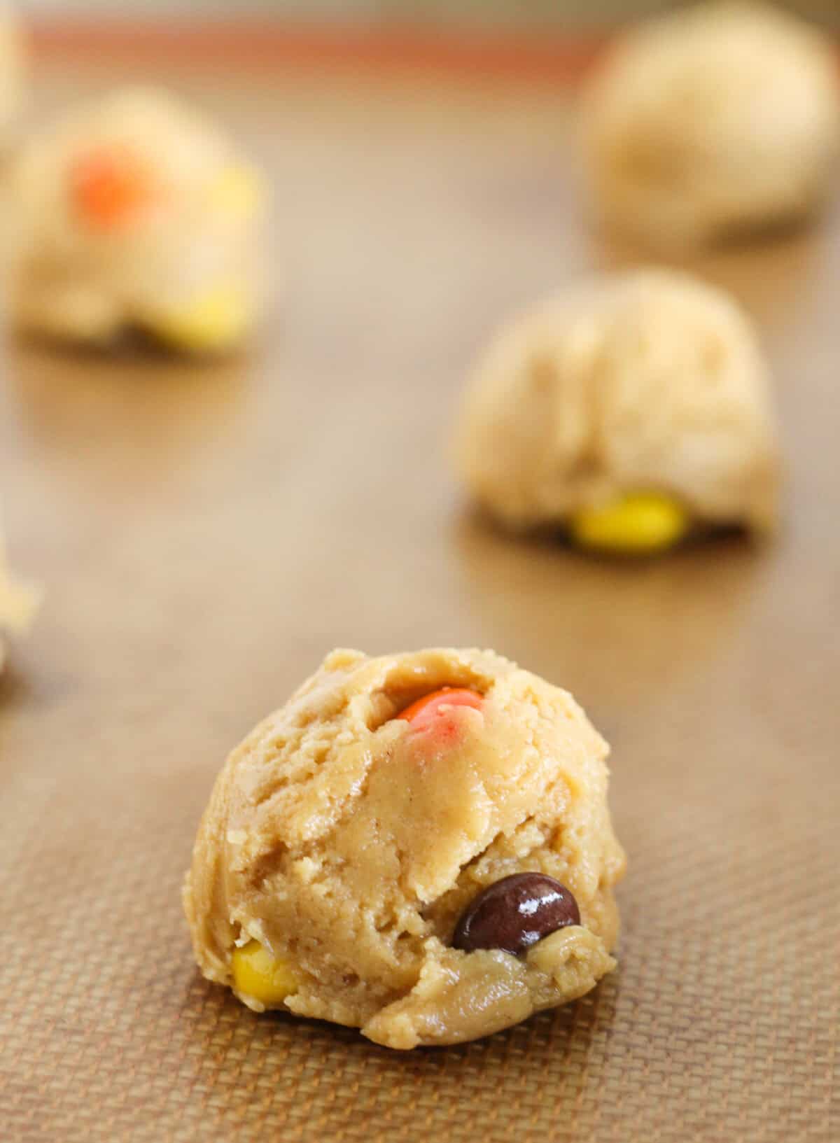 Scooping Reese's Pieces cookie dough on a baking sheet.