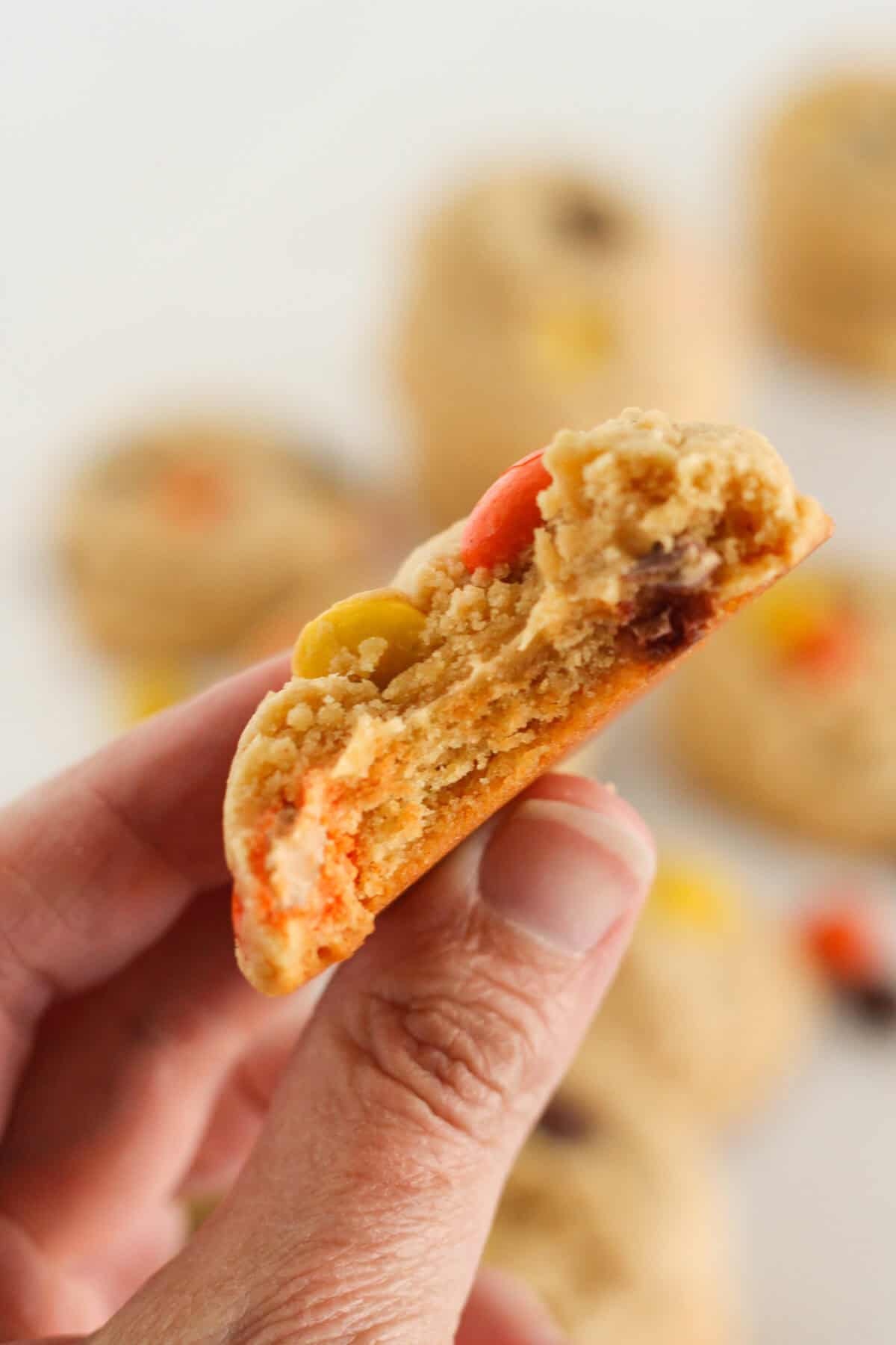 A bite taken from a Reese's Pieces cookie.
