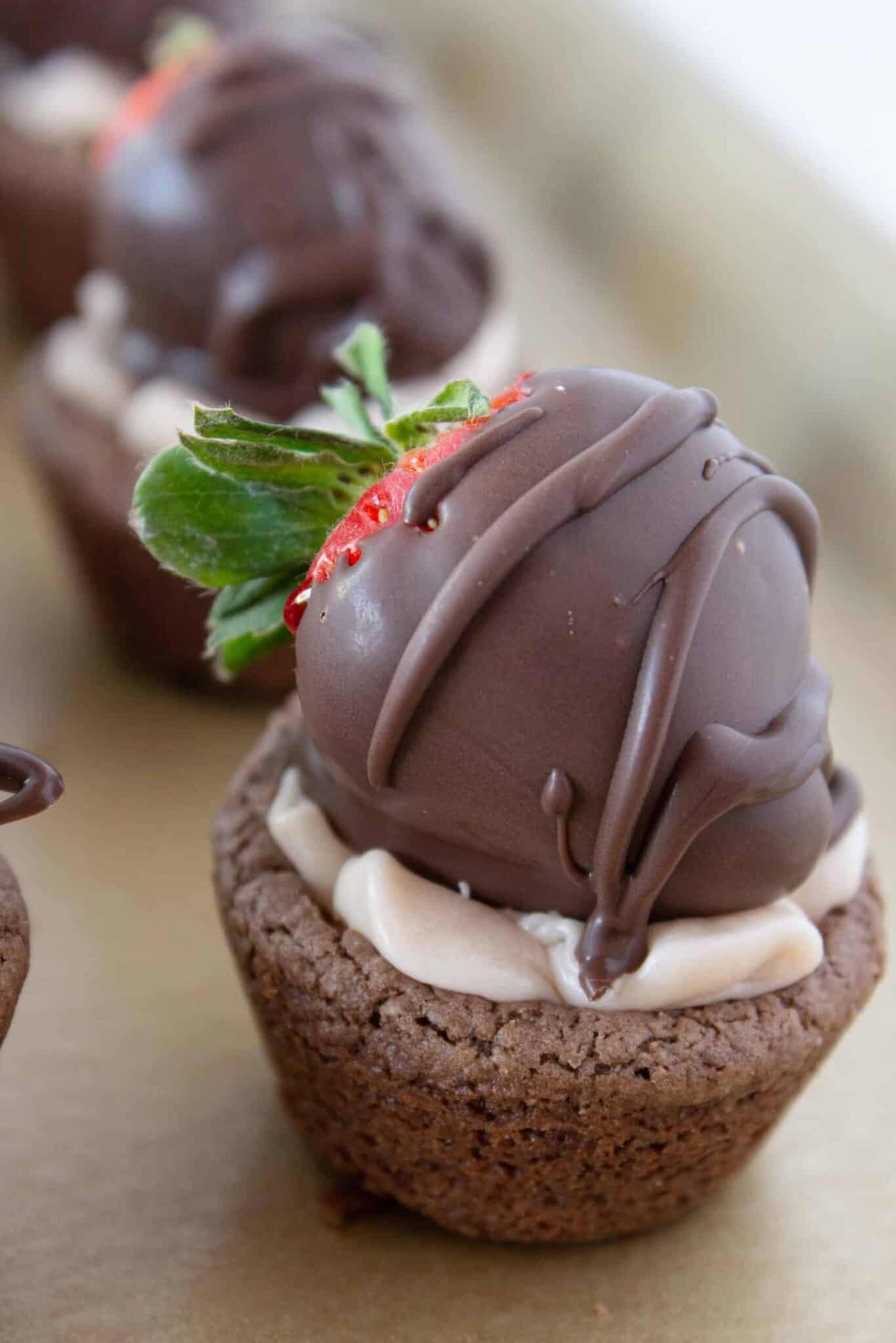 Topping each cookie with a chocolate covered strawberry.