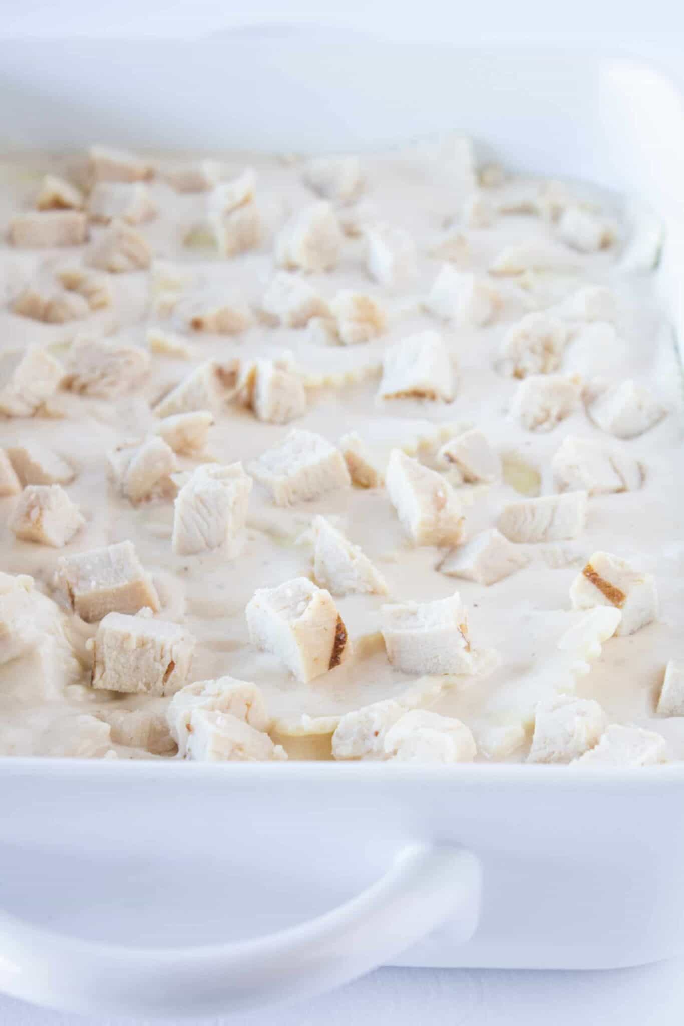Adding the Alfredo ravioli and chicken to a casserole dish.