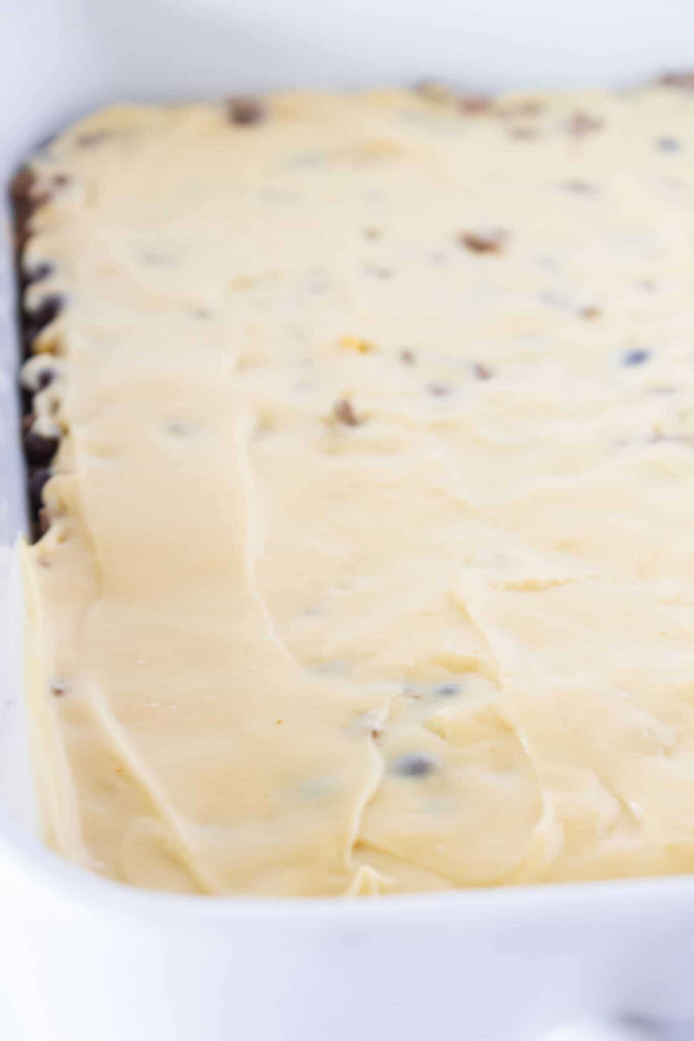 Adding the beef mixture into a prepared pan and topping with nacho cheese.
