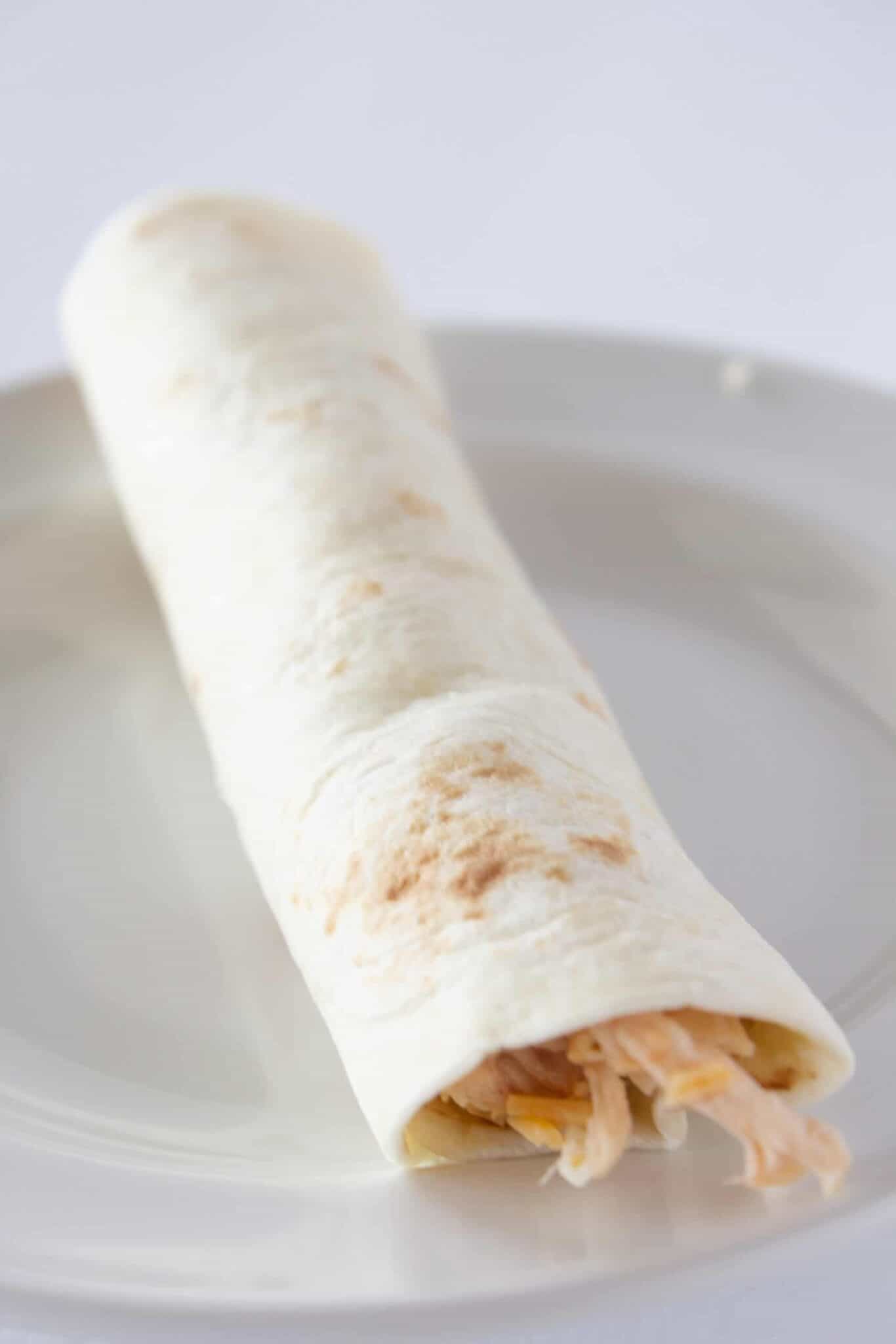 Rolling up a chicken taquito like a rolled taco.