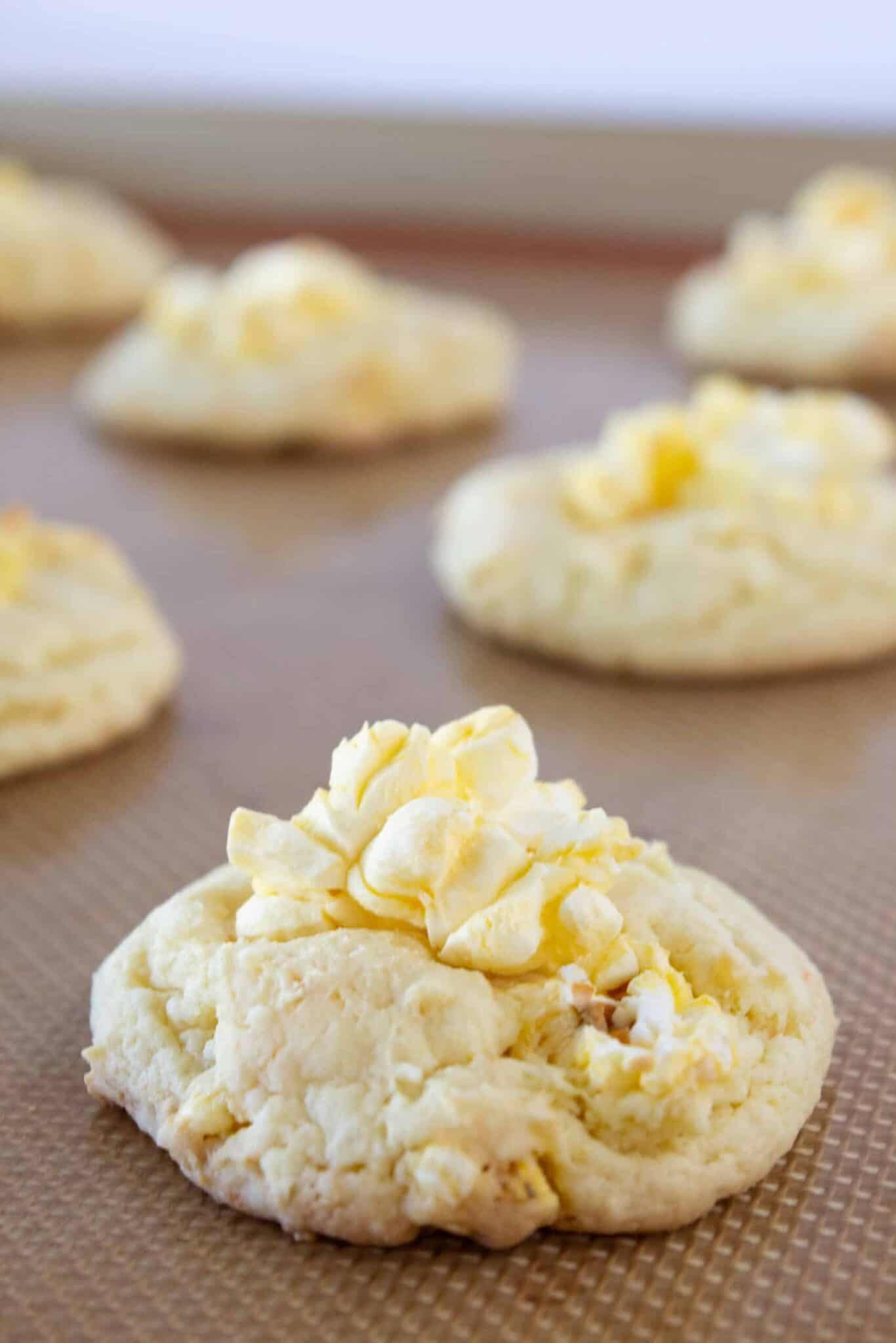 Baking the cookies and adding more popcorn to the top of each cookie.