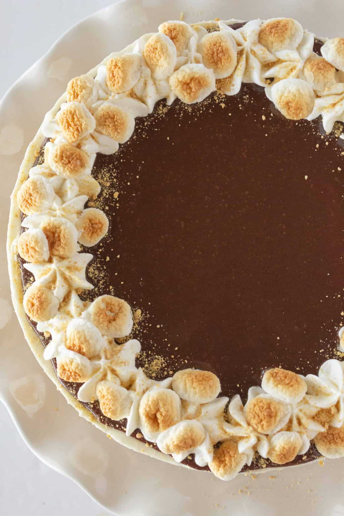 No Bake S'mores Cheesecake on a white cake plate for serving.